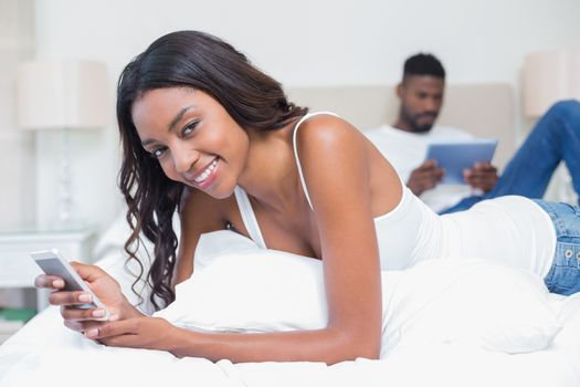 Relaxed couple using technology on bed at home in bedroom