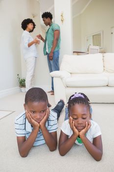 Happy siblings sitting on the floor using laptop at home in the living room