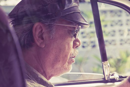 Close up image of older man with glasses driving a car