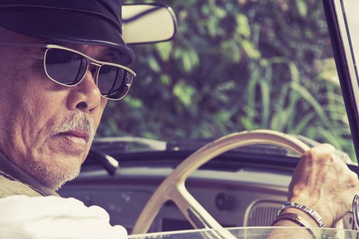 Close up image of older man with glasses driving a car