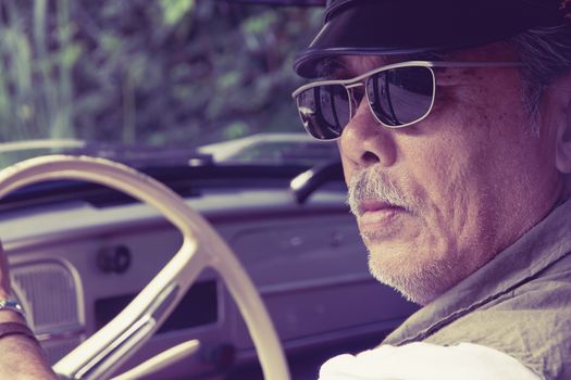 Close up image of older man with glasses driving a car