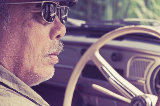 Close up image of older man with glasses driving a car