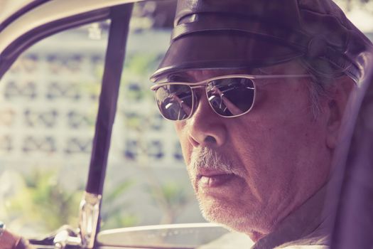 Close up image of older man with glasses driving a car