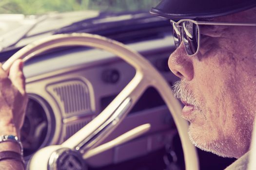 Close up image of older man with glasses driving a car