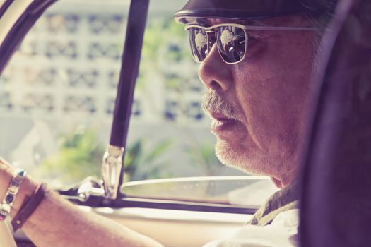 Close up image of older man with glasses driving a car