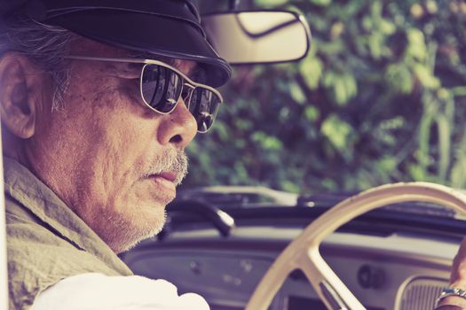 Close up image of older man with glasses driving a car