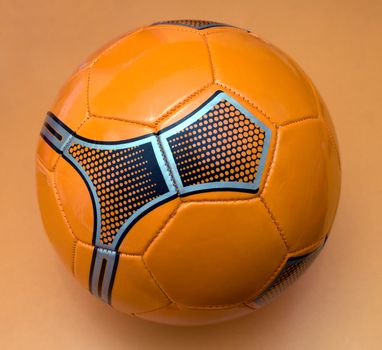 General view of the sport orange ball with a decorative pattern on a light - orange background