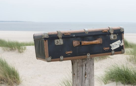 old vintage leather suitcase with beach and sea as background