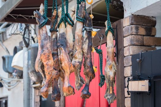 Some roasted legs of ham hanging outside a small shop in an alleyway in the countryside of Japan.