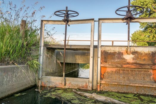 gates (headgates) and foot bridge of irrigation ditch, summer in Colorado farmland