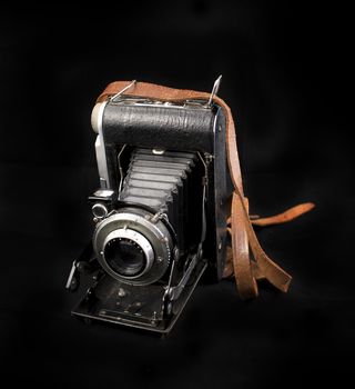 Vintage analog photo camera with bellows isolated on black background