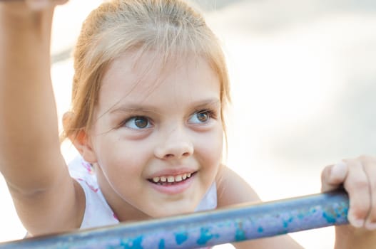 Five-year girl playing on the playground climbs the stairs