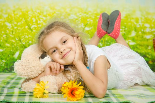 Five-year girl lies on her stomach on the mat for a picnic