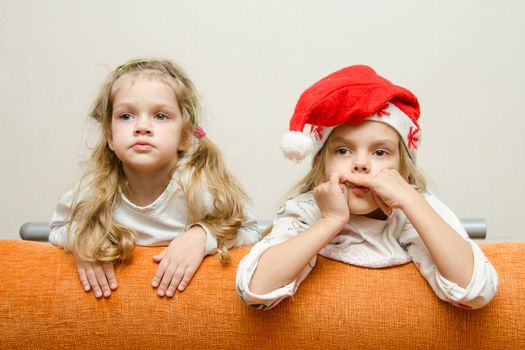Two girls enthusiastically watching the left leaning back on the couch