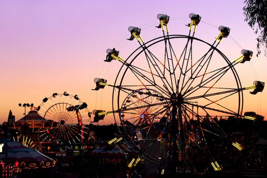 Silhouettes of carnival rides under sunset