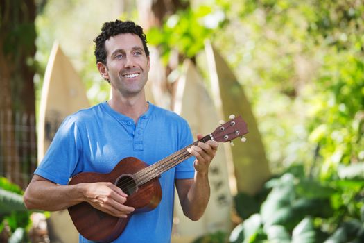 Single handsome male in blue playing ukelele