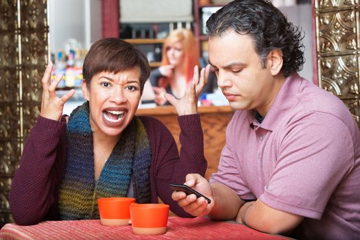 Angry woman gesturing next to indifferent husband texting