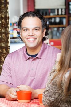 Smiling handsome African American man having coffee with friend