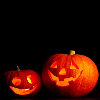 Two glowing Halloween pumpkins isolated on black background