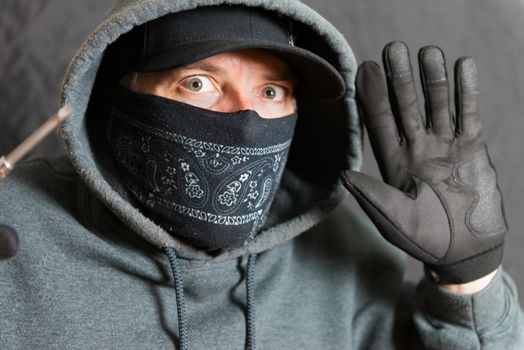 Close-up of a burglar busted, with his hands and tools up