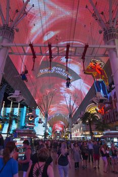 LAS VEGAS, USA - MAY 28, 2015: Tourists gather under the world's largest video screen as riders fly overhead on a zipline at Fremont Street Experience in Las Vegas