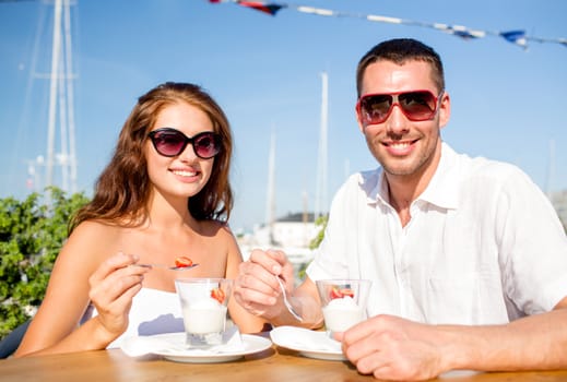 love, dating, people and food concept - smiling couple wearing sunglasses eating dessert at cafe