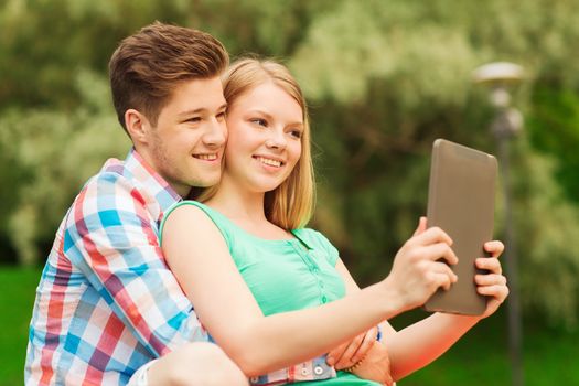 vacation, holidays, technology and friendship concept - smiling couple with tablet pc computer making selfie in park