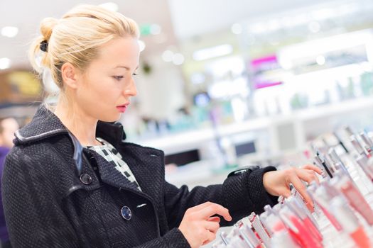 Beautiful blond lady testing  and buying cosmetics in a beauty store.