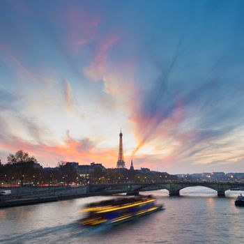 Beautiful colorful sunset over Eiffel Tower and Seine river. Paris, France. Illuminated tourist boat crousing on the river, enjoying the romantic view. Square composition. Copy space.