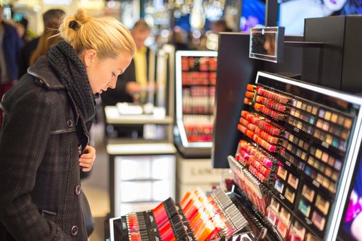 Beautiful blond lady testing  and buying cosmetics in a beauty store.