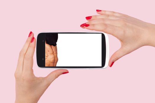 Online dating. Female hands holding smartphone with picture of handsome man isolated on pink background. Flirting and relationship in the information age.