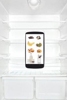 Open empty white refrigerator with smartphone with groceries on screen. Modern high tech groceries shopping
