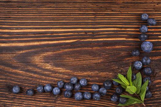 Fresh blueberry background with copyspace. Ripe fresh blueberries on rustic wooden background, top view. Healthy summer fruit eating. 