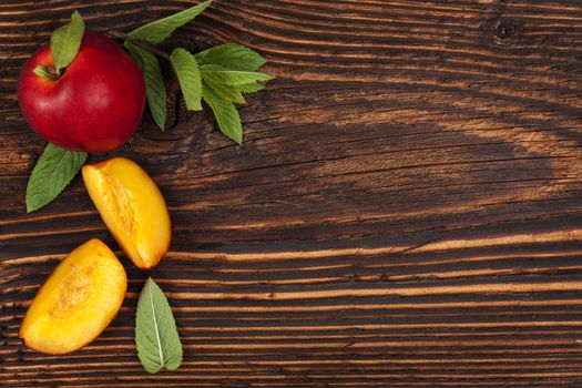 Nectarine background with mint leaves on wooden table with copyspace, top view. Healthy fresh fruit eating. 