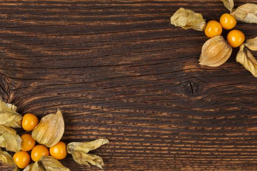 Physalis background with copyspace. Ground cherry on wooden rustic table top view. Healthy fresh fruit eating. 