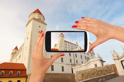 Bratislava castle tourism. Female tourist taking picture of Bratislava castle on smartphone. Tourism concept. 