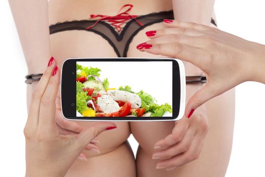 Hot sexy ass in panties and hands with handcuffs backview isolated on white with smartphone screen with healthy colorful salad. Healthy eating and sexy figure. Sexy, hot, provocative woman. 
