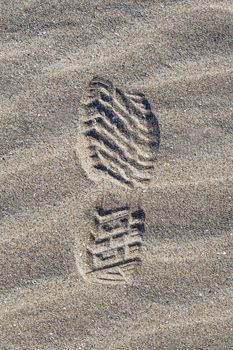 Close up top view of one shoe print, man footprint on sand with holiday concept.