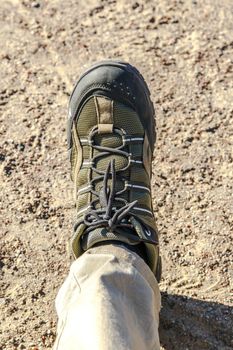 Top view of man foot with trekking shoe, on ground floor background.