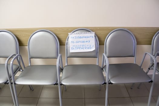 Row of chairs with an attached note in empty corridor
