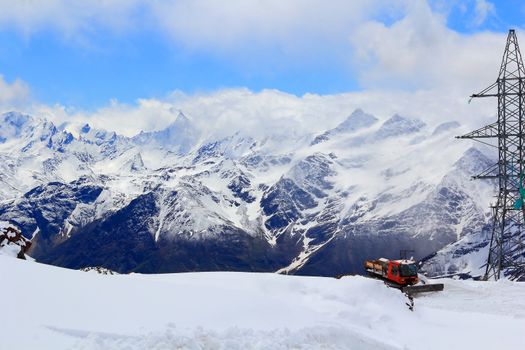 Winter landscape of Caucasus mountains with snowplow machine