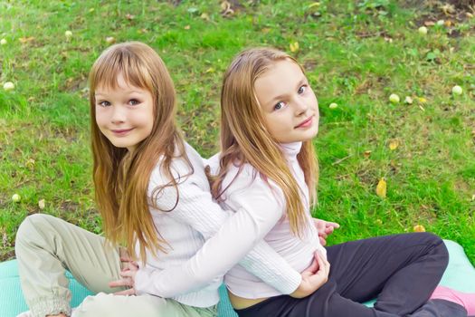 Photo of two girls sitting on grass in summer