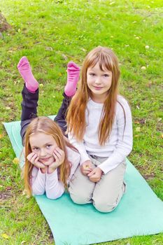 Photo of two girls sitting on grass in summer