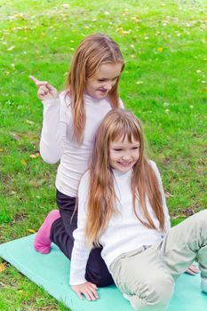 Photo of two girls sitting on grass in summer