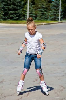 Learning girl on roller skates in summer