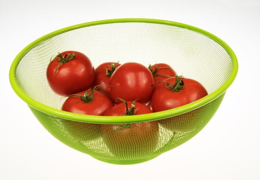 Six red tomatoes in green basket on white isolated background.Horizontal view.