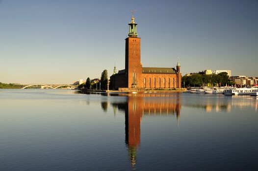 The Stockholm Stadshuset in early morning light perfectly reflected in still water.