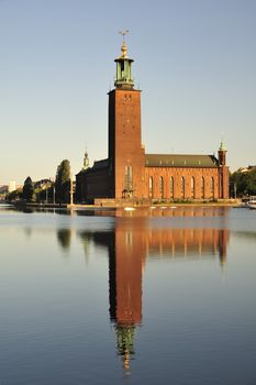 The Stockholm Stadshuset in early morning light perfectly reflected in still water.