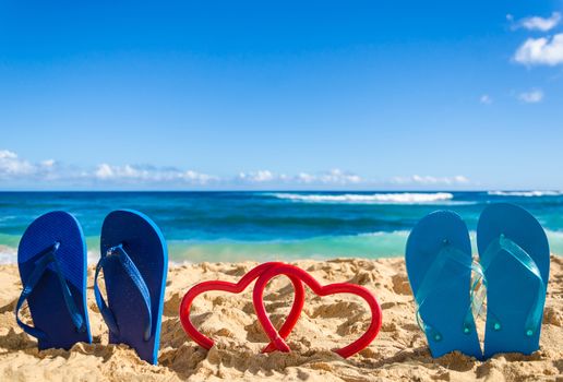 Flip flops with heart shapes on the sandy beach in Hawaii, Kauai (romantic concept)