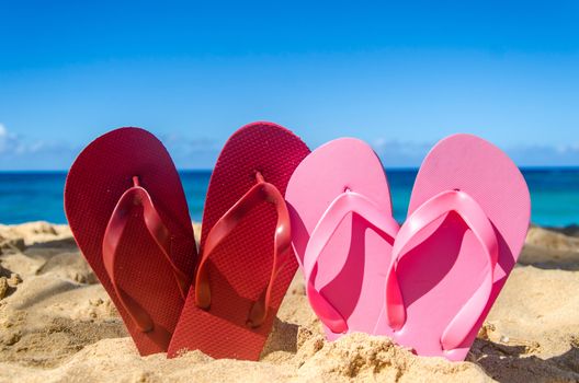 Red and pink flip flops in heart shapes on the sandy beach in Hawaii, Kauai (romantic concept) 